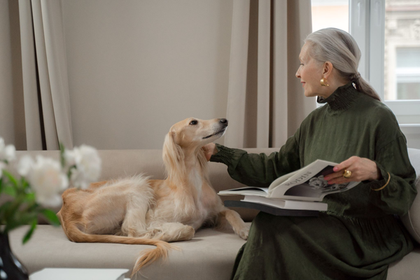 Older Lady Sitting On A Sofa With A Saluki Dog